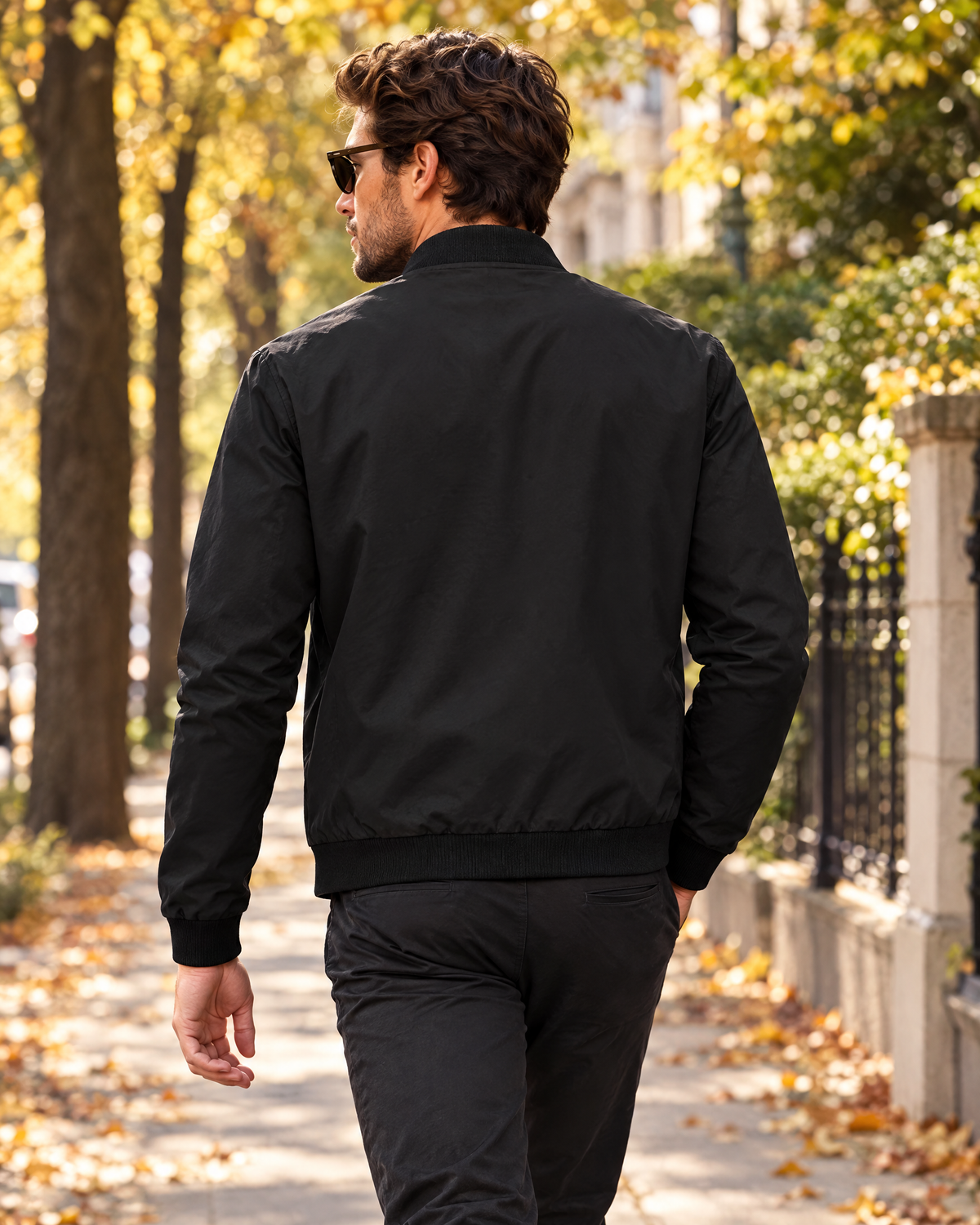 Back view of man walking in Marlon black zip-up bomber jacket in autumn light