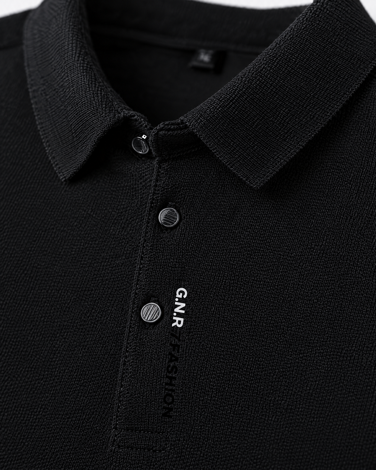 Close-up of black men's polo shirt ribbed collar, buttons and placket print