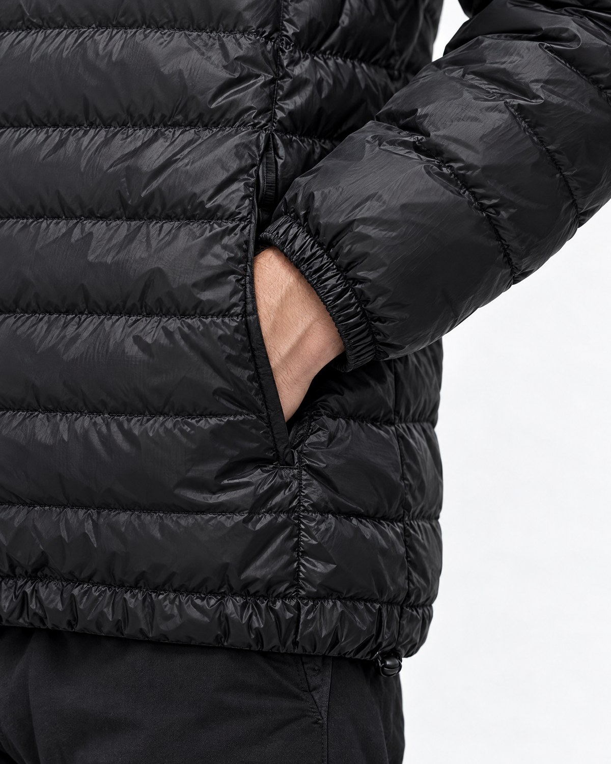 Elastic cuff, hem and zip pocket of men's black lightweight puffer jacket